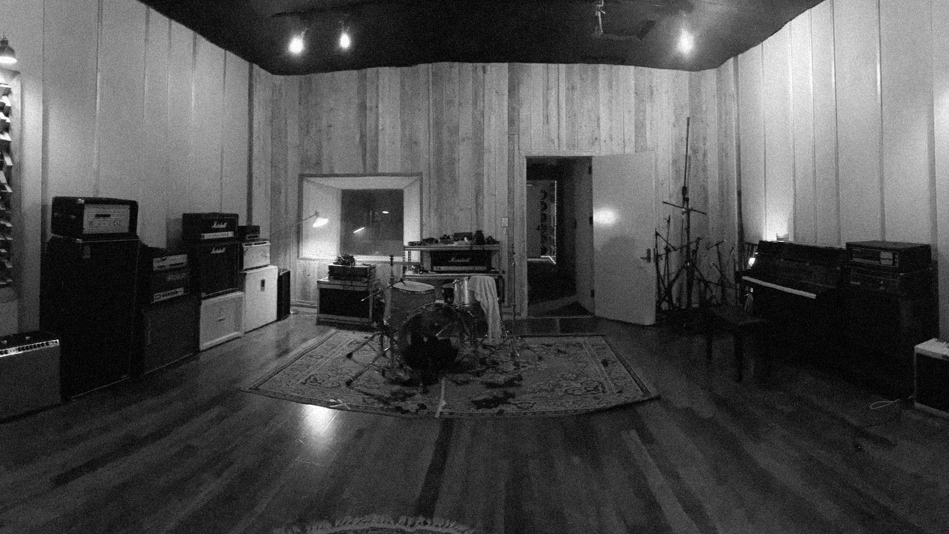 The wood-panelled live room with amps, drums and a piano