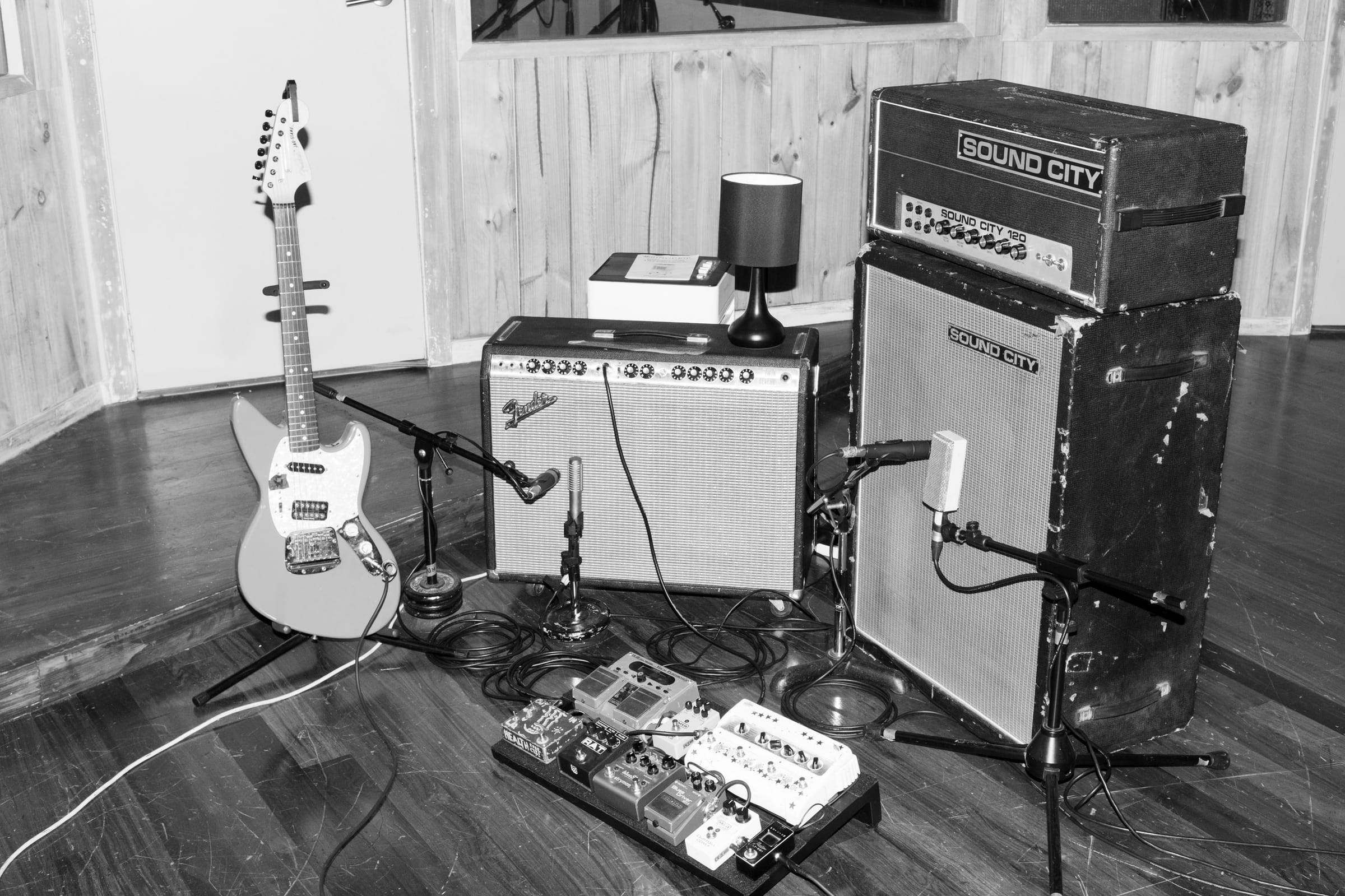 A guitar, amplifiers and microphones set up for recording